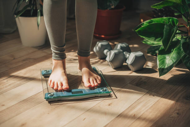 A young woman is weighing herself in a weighing scale A young woman is weighing herself in a weighing scale